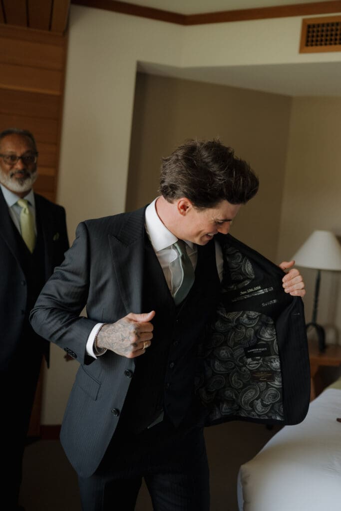 A groom getting ready for his wedding day at Wickaninnish Inn in Tofino BC looking inside his suit jacket.