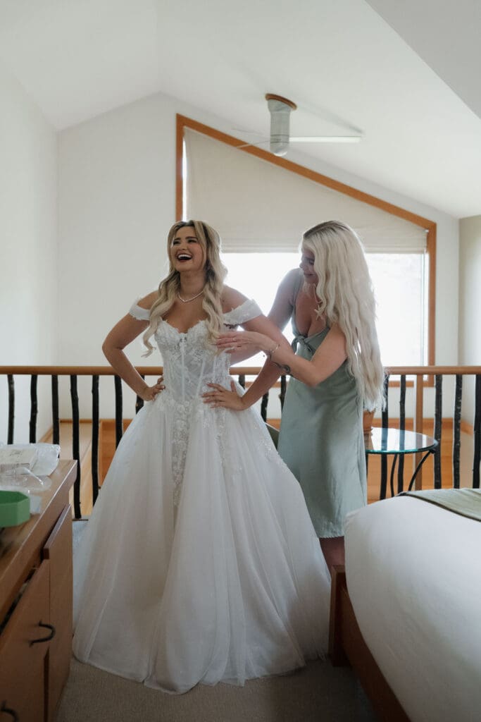 A bride gets ready before her wedding with help from the maid of honour.