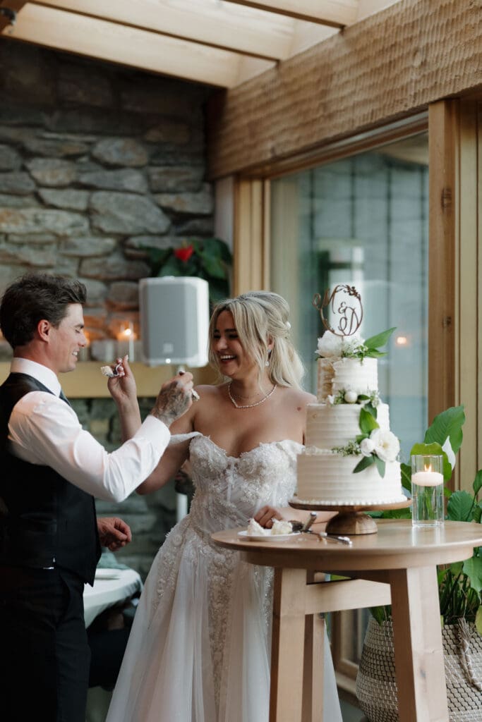 A newly married bride and groom feed each other a piece of their wedding cake during their reception at Hemlock Hideaway.