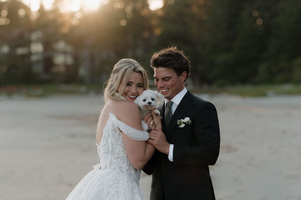 Romantic bride and groom wedding portraits with their dog at the beach in Tofino on Vancouver Island with golden hour rays shining through the trees behind them