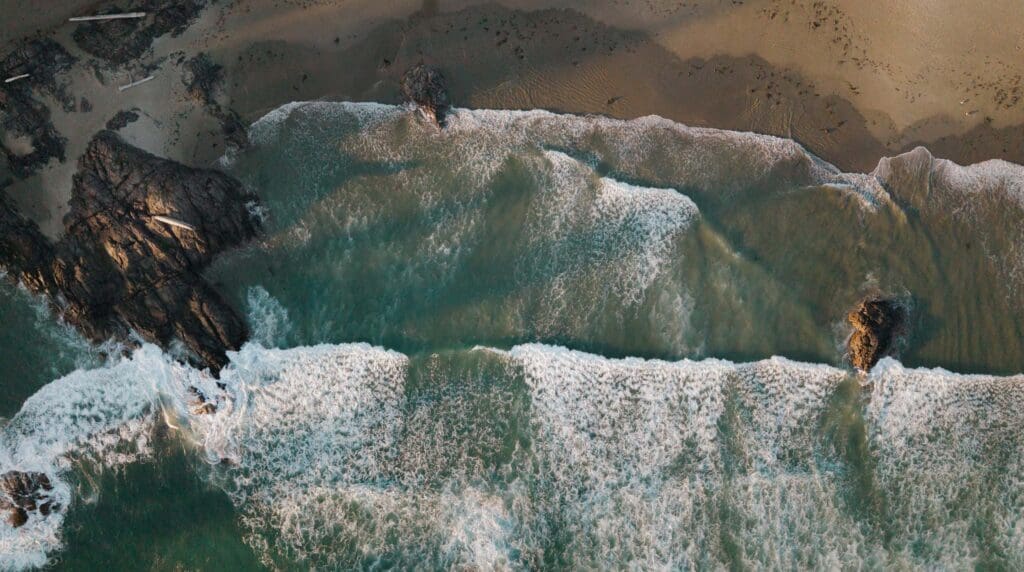 Aerial view of the waves crashing onto shore at a private beach wedding ceremony at the Wickaninnish Inn on Vancouver Island, captured via drone