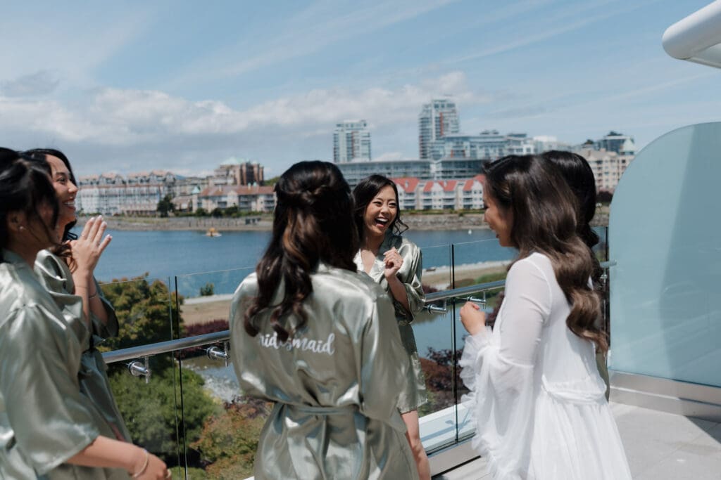 Victoria BC Wedding Videographer and Photographer captures a bridal party on the patio at Inn at Laurel Point with the cityscape in behind them for this elegant mini-destination wedding on Vancouver Island.